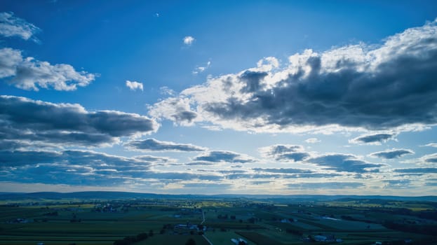 Blue sky and multiple clouds background showing a horizon and a hidden sun