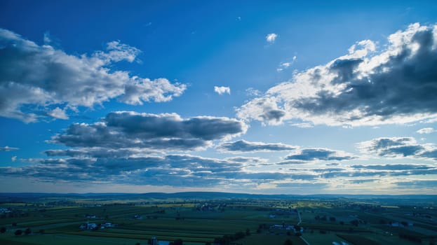Blue sky and multiple clouds background showing a horizon and a hidden sun
