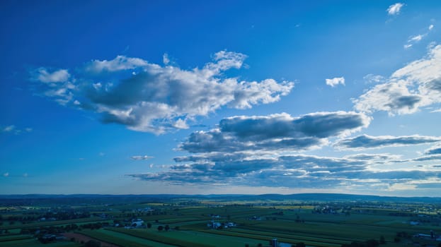 Blue sky and multiple clouds background showing a horizon and a hidden sun