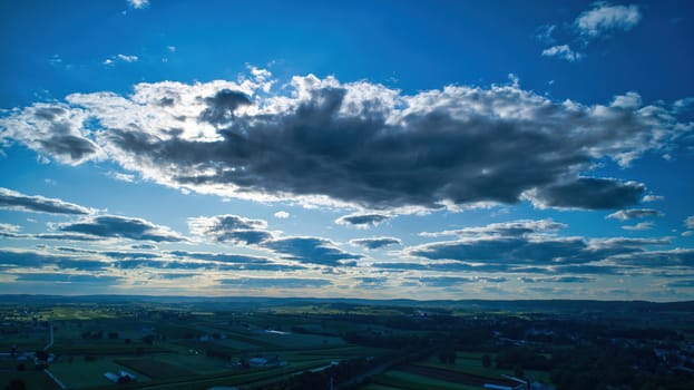 Blue sky and multiple clouds background showing a horizon and a hidden sun