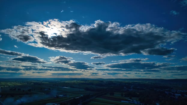 Blue sky and multiple clouds background showing a horizon and a hidden sun