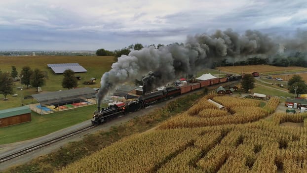 Aerial of double header antique restored steam engines puffing along countryside