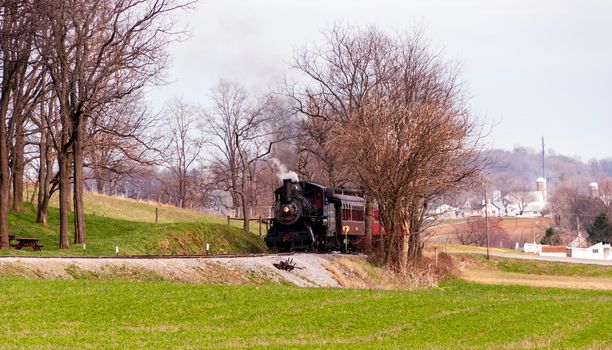 Steam train pulling passenger cars on a winter day