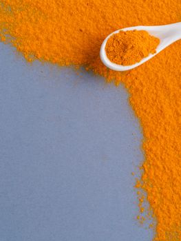 Turmeric Powder or Curcuma longa and white spoon with turmeric powder on gray background. Top view. Copy space for text.