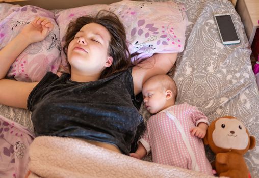 Young mother and her baby, sleeping in bed.