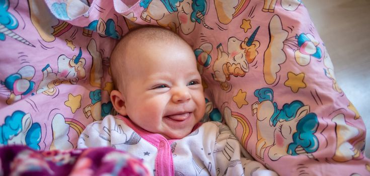 pretty smiling baby girl and toy rabbit lying in light background.