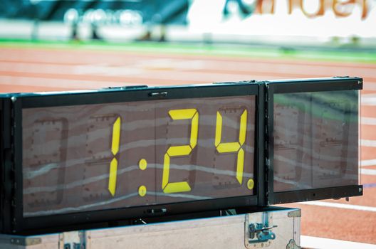 Digital sport chronometer in sport event next to athletic stadium tracks