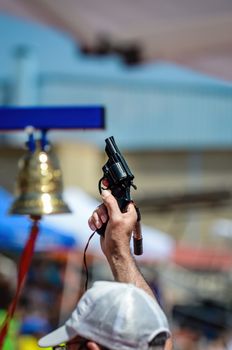 Blue information marker for athletics race run by CEMA track judge shooting gun near a bell