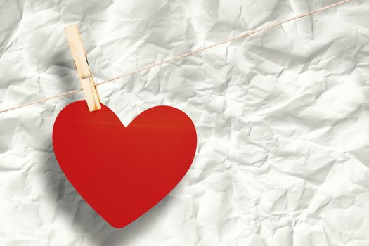 Heart hanging on line against crumpled page