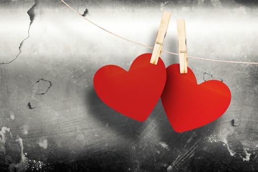 Hearts hanging on line against grey background