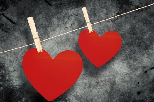 Hearts hanging on a line against grey background