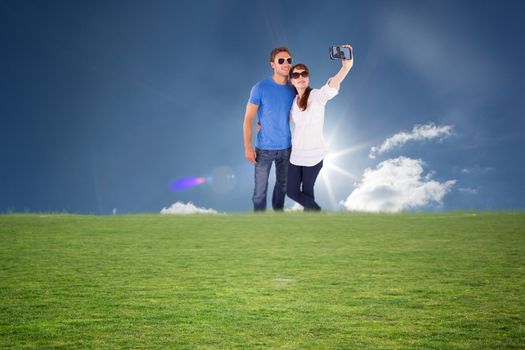 Couple using camera for picture against cloudy sky with sunshine