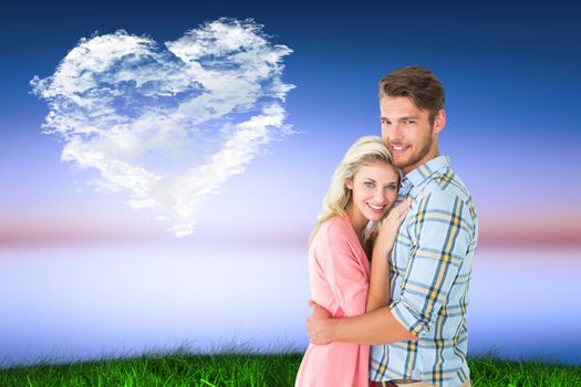 Attractive couple embracing and smiling at camera against cloud heart