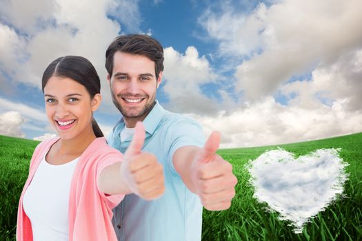 Happy couple showing thumbs up against cloud heart