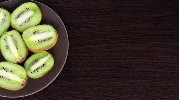 sliced kiwi on a plate, on a dark background	
