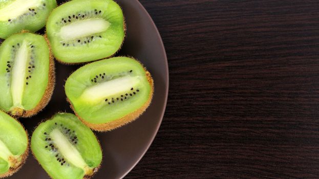 sliced kiwi on a plate, on a dark background	