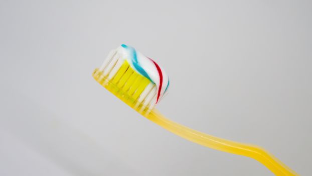 toothpaste of three colors with a toothbrush on a white background