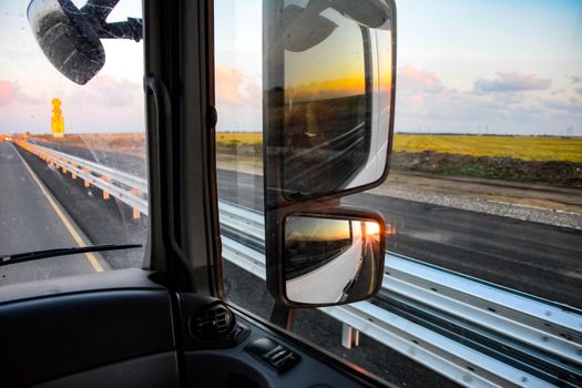 In the cockpit of a truck at dawn. Large rear-view mirrors