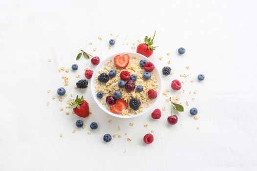 Oatmeal porridge in bowl topped with fresh berries, and homemade crunchy granola