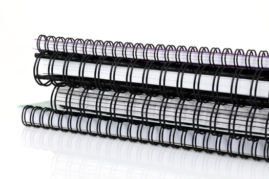 A pile of spiral bound notebooks on white