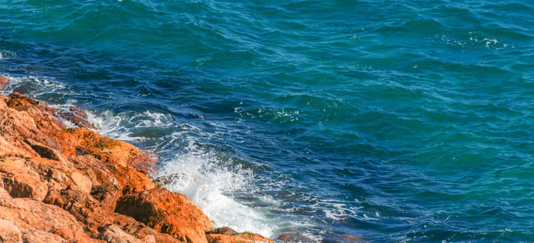 high cliff above the sea, summer sea background, many splashing waves and stone, sunny day