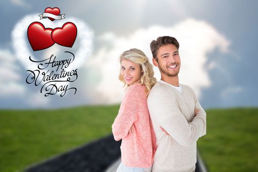 Attractive couple smiling with arms crossed against road on grass