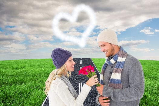 Attractive man in winter fashion offering roses to girlfriend against road on grass