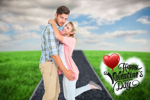 Handsome man hugging his girlfriend against road on grass