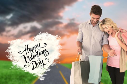 Attractive young couple holding shopping bags against cloud heart