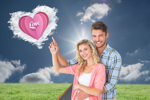 Attractive young couple embracing and pointing  against cloud heart