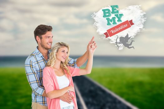 Attractive young couple embracing and pointing  against cloud heart