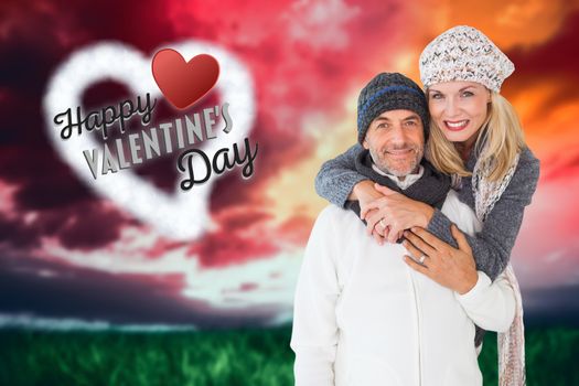 Happy couple in winter fashion embracing against green grass under red and purple sky