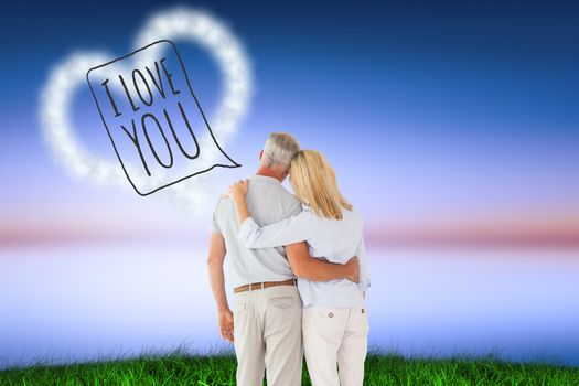 Happy couple standing and looking against green grass under blue and purple sky