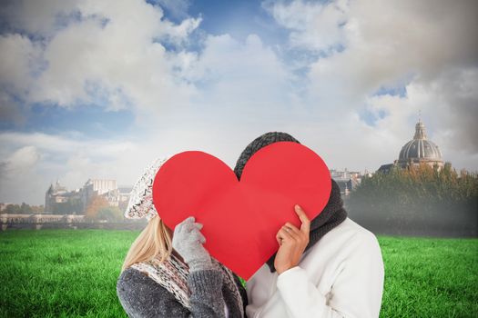 Couple in winter fashion posing with heart shape against paris under cloudy sky
