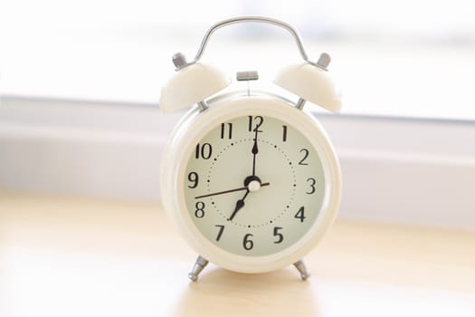 Alarm clock on white table with soft light in the morning, selective