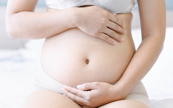 Pregnancy woman on white bed background, health care and medical concept,Young woman expecting a baby