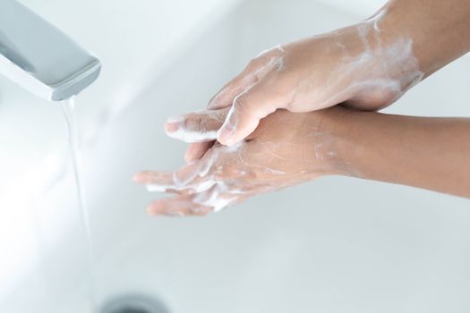 Closeup woman's hand washing with soap in bathroom, selective focus