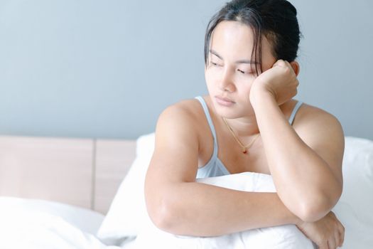 Closeup woman sitting on bed in the bedroom with thinking or depressed feeling, selective focus