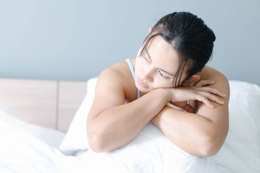 Closeup woman sitting on bed in the bedroom with thinking or depressed feeling, selective focus