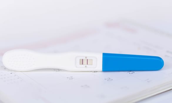Pregnancy test on calendar background, health care concept