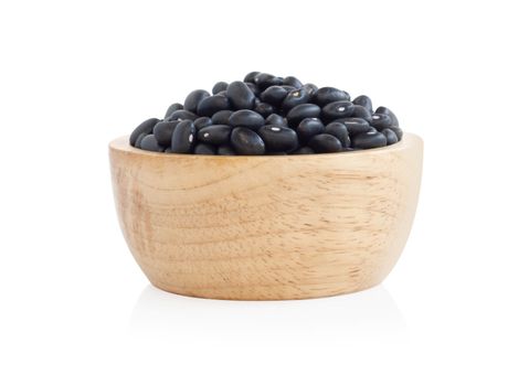 Closeup black beans seeds in wooden bowl on white background, healthy food concept