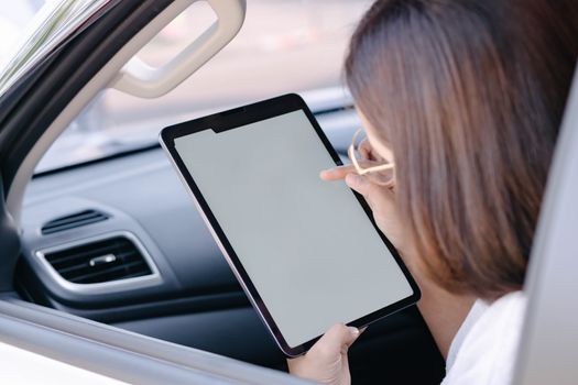 Closeup asian woman using digital tablet in a car with happy face