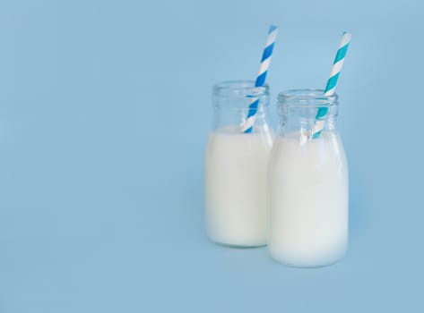 Bottle of fresh milk with straw on light blue background, food healthy concept