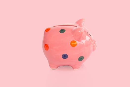 Pink ceramic piggy bank on pink background, saving money concept