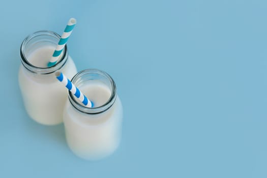 Bottle of fresh milk with straw on light blue background, food healthy concept