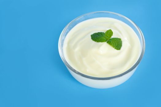 Close up yogurt  in glass bowl  with wooden spoon on blue background