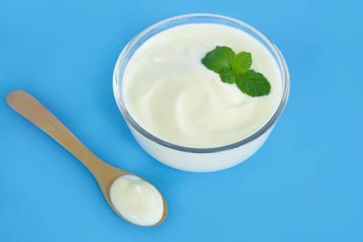 Close up yogurt  in glass bowl  with wooden spoon on blue background