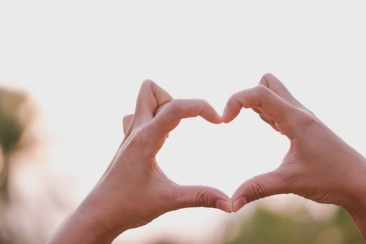 Closeup hand make heart shape with nature background, selective focus