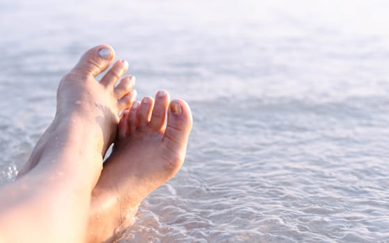 Beautiful woman's legs relaxing on the beach with light of sunset, Holiday concept