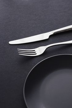 Empty plates and silverware on black background, premium tableware for holiday dinner, minimalistic design and diet concept